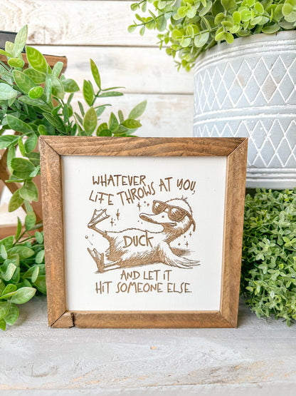 Whatever life throws that you duck and let it hit someone else. Laser Engraved Wood Sign.